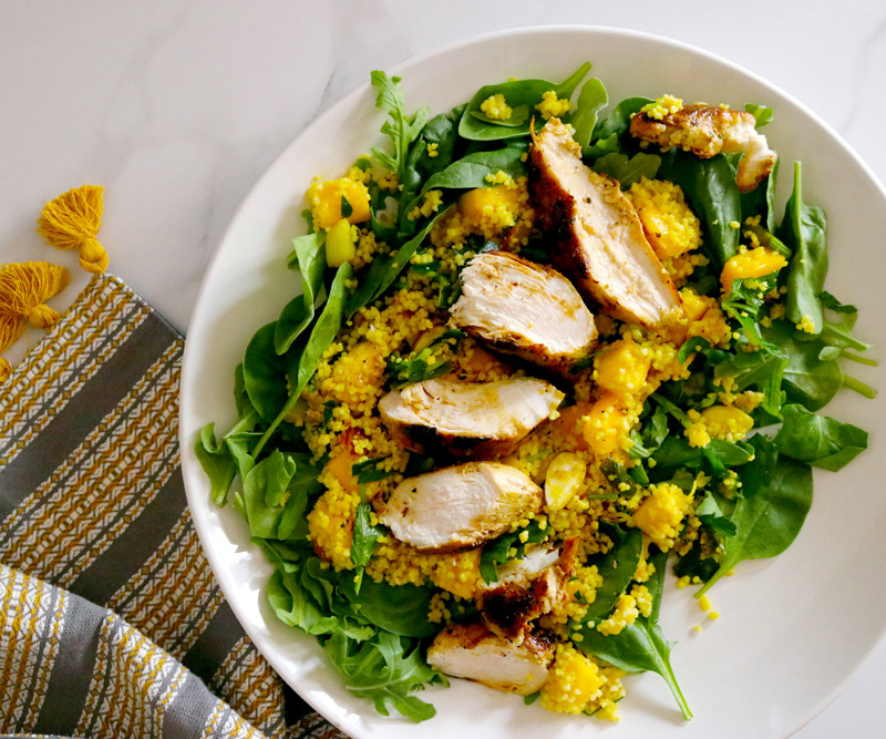 a plate of Curried Chicken Mango Couscous Salad on a marble counter top