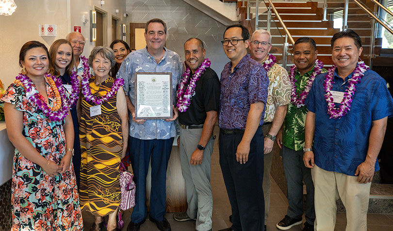 Group of politicians, healthcare executives and community leaders wearing lei in lobby of new urgent care clinic.