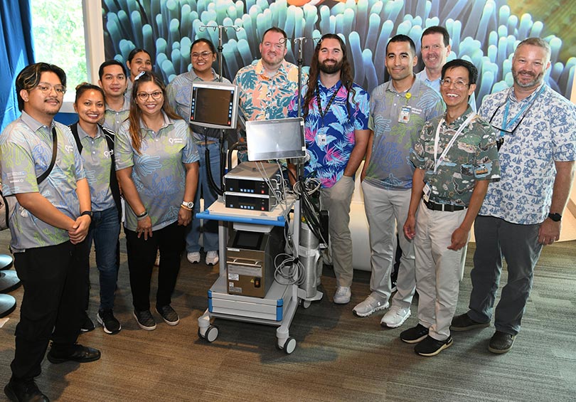 Group shot of fundraisers standing around an ECMO machine.