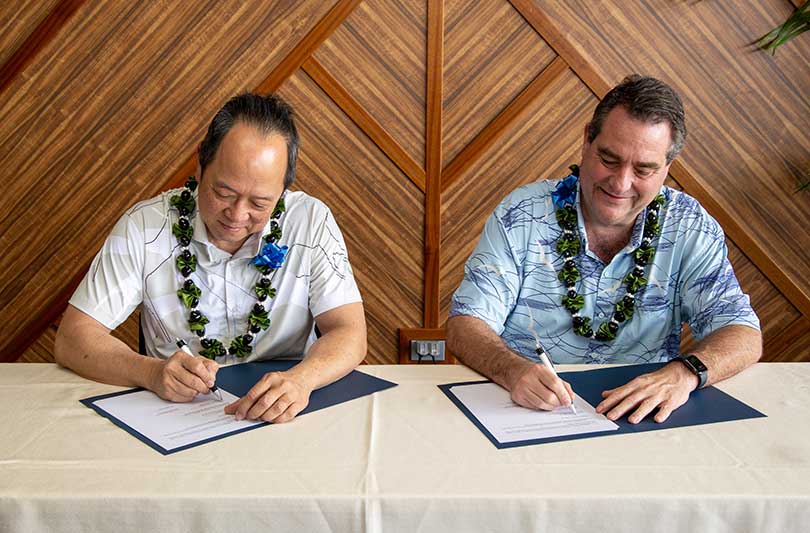 Two men at a table formally signing documents of agreement.