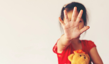 Young child holding up her hand to signal STOP.