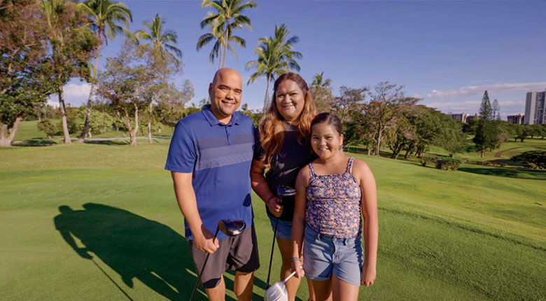 Smiling husband, wife and child on the golf course.