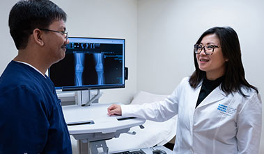 A male medical assistant and female doctor review an X-ray of a knee in an exam room at Straub Benioff Medical Center.