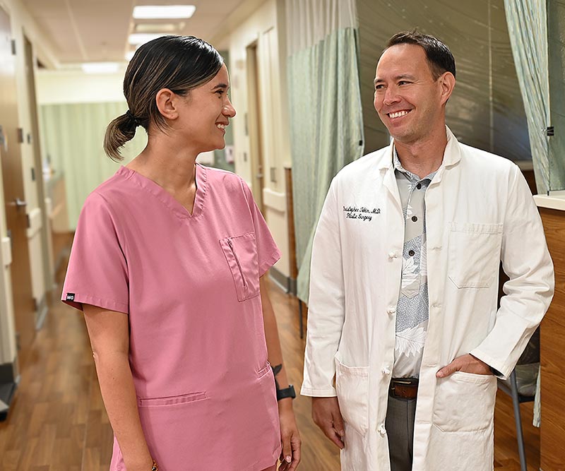 Two medical care providers in a clinic hallway having a friendly discussion.