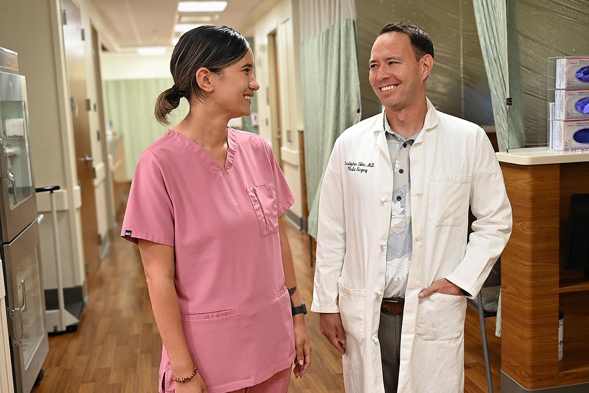 Two medical care providers in a clinic hallway having a friendly discussion.