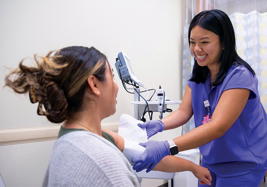 Smiling nurse adjusting a patient's blood pressure sleeve.