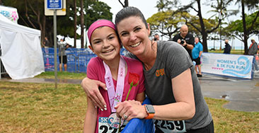 Race finishers: mother with tween daughter wearing medals and smiling.