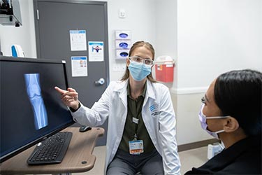 Doctor with patient looking at X-ray image on a computer screen.