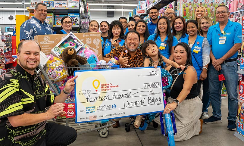 Group shot in Walmart store with giant check and shopping cart full of toys.