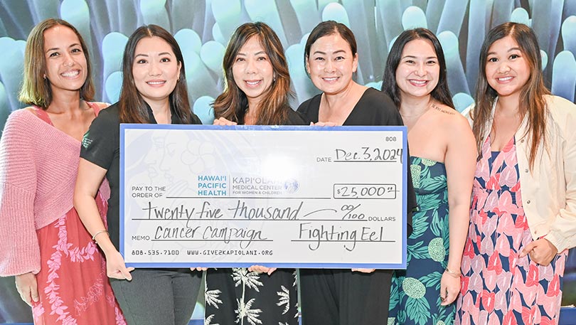 Six smiling women holding a giant check.