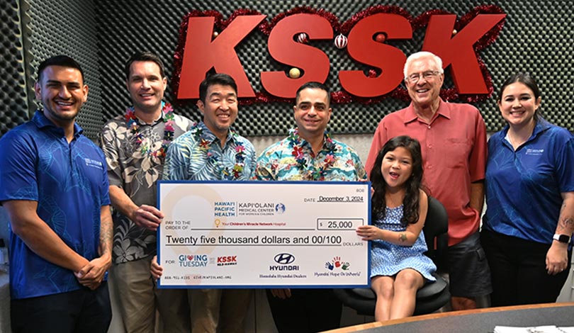 Group shot in front of KSSK sign with giant check.