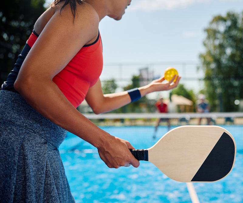 woman serving the ball while playing mixed doubles in pickleball