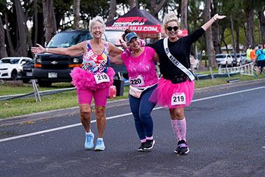 Female runners smiling and wearing bright pink tutus.