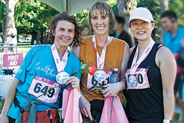 Three female runners smiling and wearing medals.