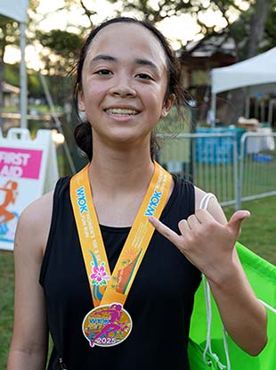 Race finisher wearing medal holding up a shaka.