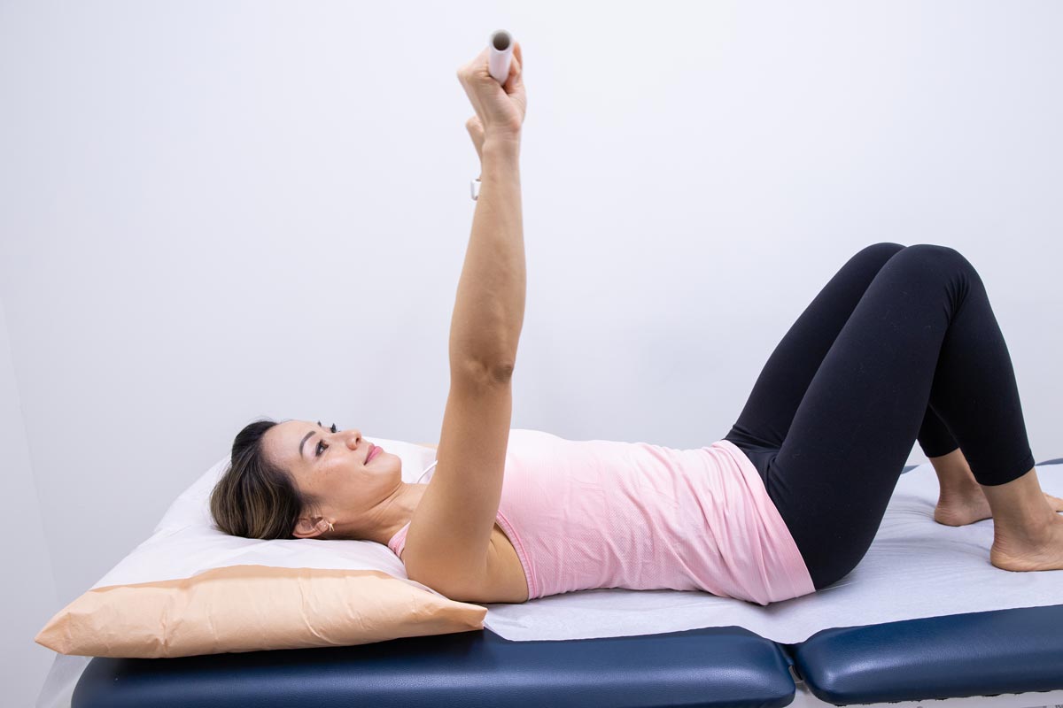 a women lies on her back holding a stick above her head