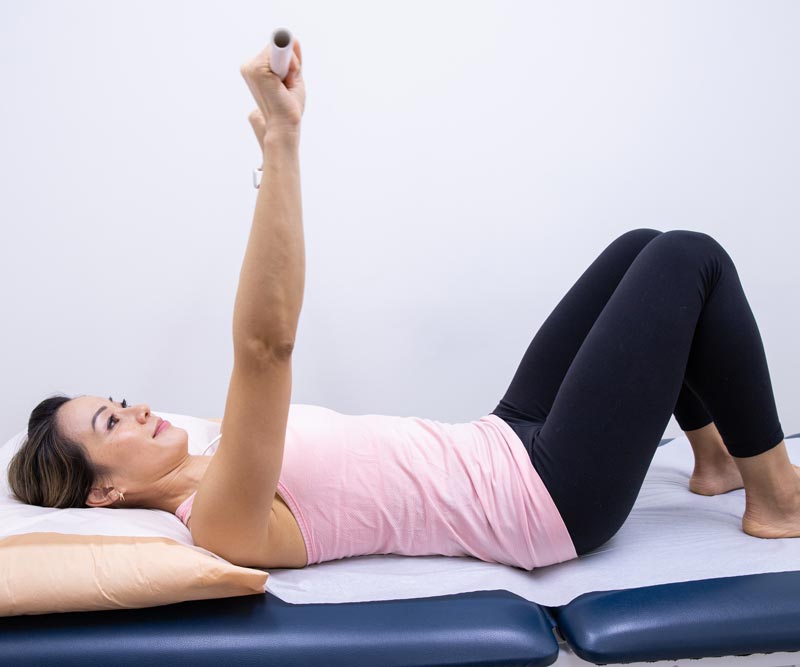 a women lies on her back holding a stick above her head