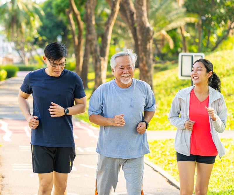 young couple walks along a path outdoors with elderly father