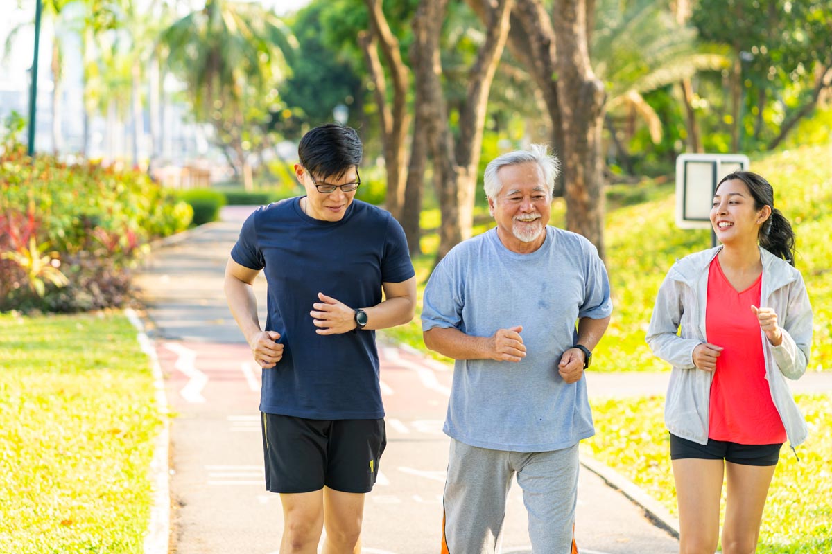 young couple walks along a path outdoors with elderly father