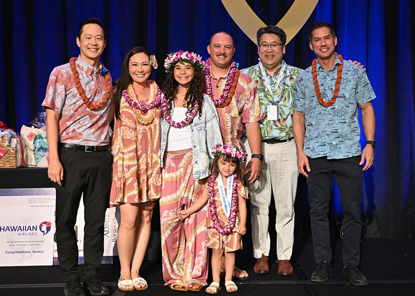 Group shot of healthcare leaders, young patient and her family, all wearing lei.