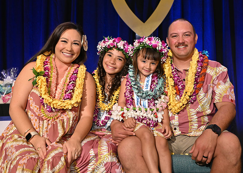 Beautiful family with two young girls all draped in lei.